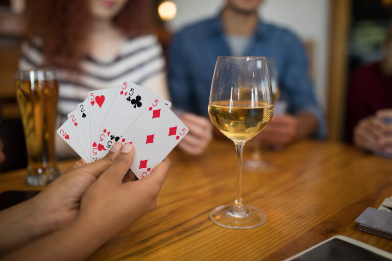 Mid section of friends playing cards in bar