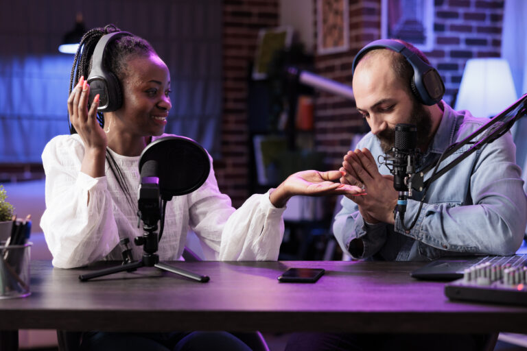 Cohosts presenting religion podcast in professional studio, teaching prayers to audiences. Presenter using high quality recording setup to film spirituality conversation, doing hands together gesture
