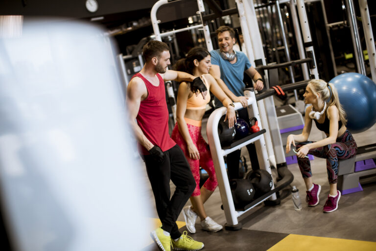 Group of young people in sportswear talking in a gym after a workout