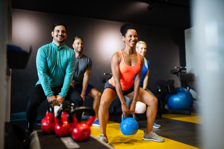 Group of sportive young people in gym. Happy fit friends workout, exercise in fitness club