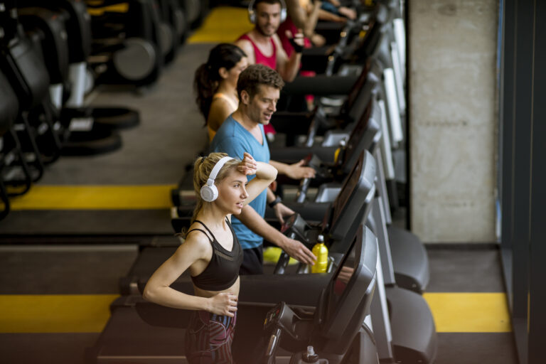 Top view at group of young people running on treadmills in modern gym