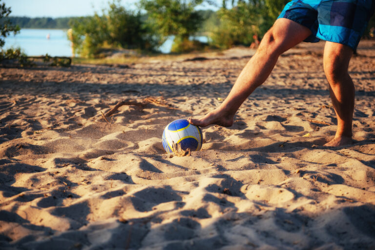 young guy playing volleyball on the beach.